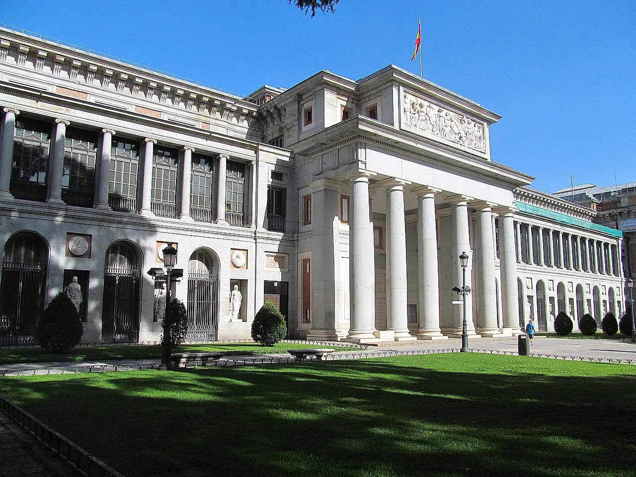 The neoclassical Prado Museum with its columns and a green lawn on a sunny day