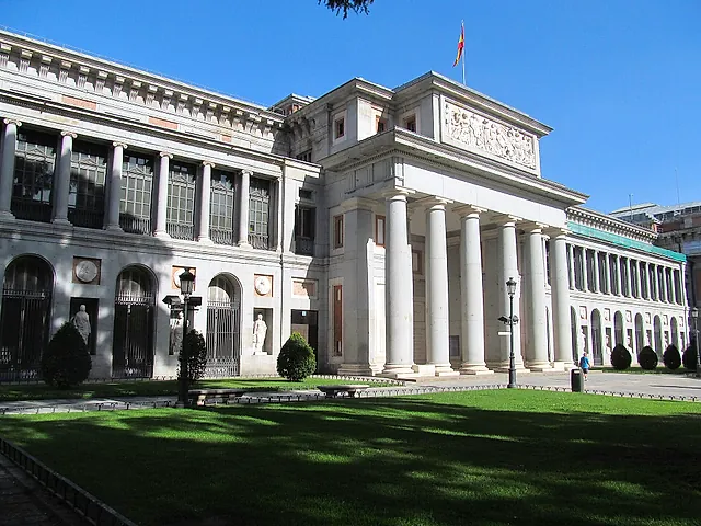The neoclassical Prado Museum with its columns and a green lawn on a sunny day