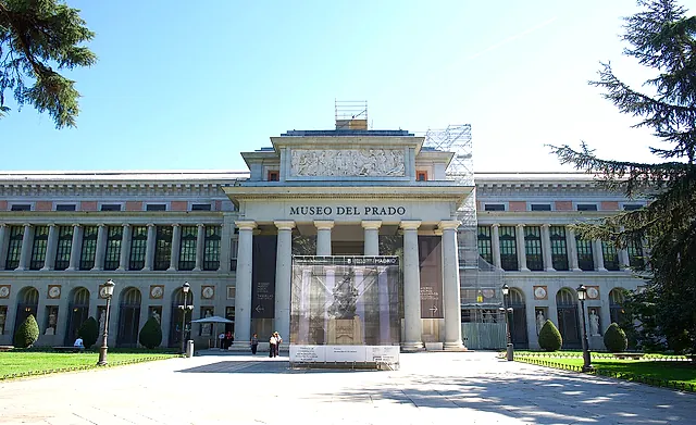 The main front of the Prado Museum, with the museum name over the portico and a lawn in front