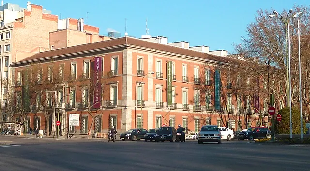 The façade of the Thyssen-Bornemisza Museum seen from the Paseo del Prado, with trees in front